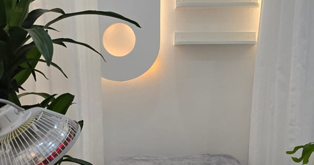 A treatment room with a heat lamp and a bed made up for a massage in District 1