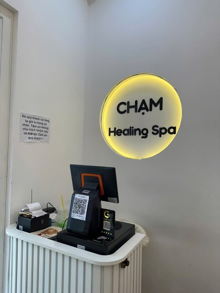 The reception desk at Chạm Spa in District 1 beneath the illuminated Chạm Healing Spa sign
