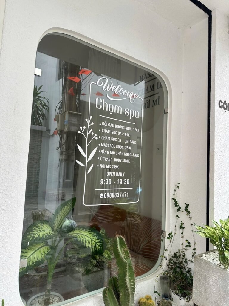 The Chạm Spa shopfront window in District 1, listing services and opening hours