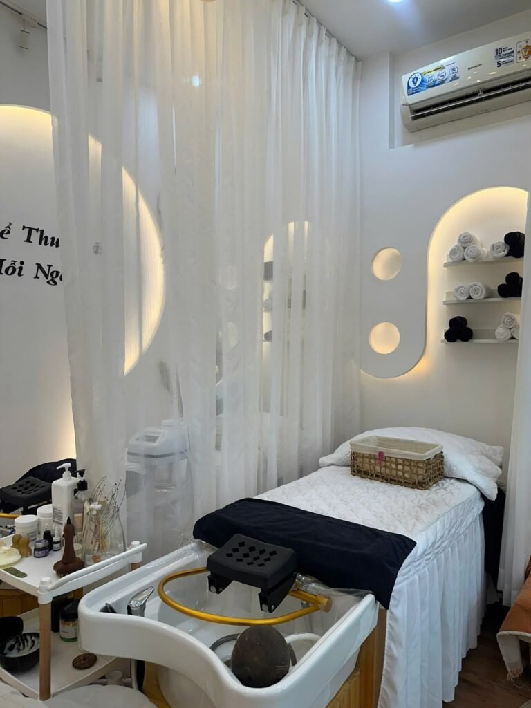 A treatment room at Chạm Spa with a made-up bed, curtains and warm wall lighting