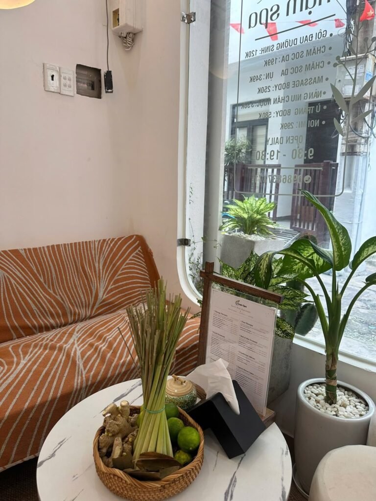 The waiting lounge at Chạm Spa with a sofa, plants and a street-facing window